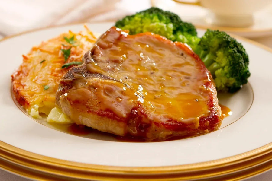  pork rib chops with a golden-brown sear on a white ceramic plate with hash browns and broccoli