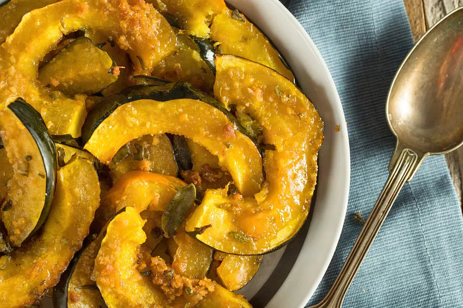 Roasted acorn squash halves glazed with Mrs. Ruth's Apple Pecan Jam, golden and caramelized, garnished with fresh thyme on a parchment-lined baking sheet